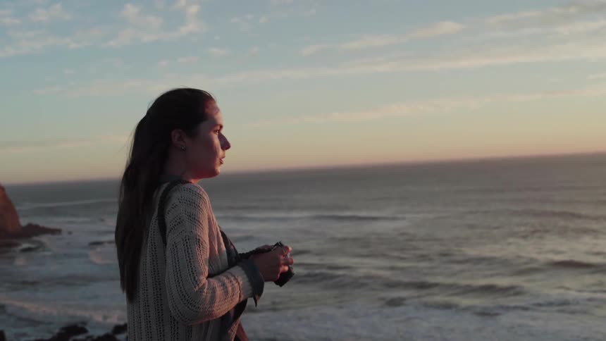 Woman takes a picture at the edge of a large body of water