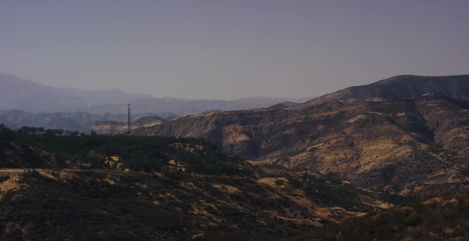 A scenic drive through a vast, dry mountain range on a hazy day