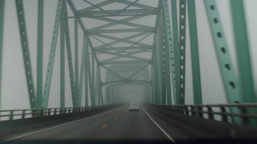Cars drives across a bridge on a foggy day