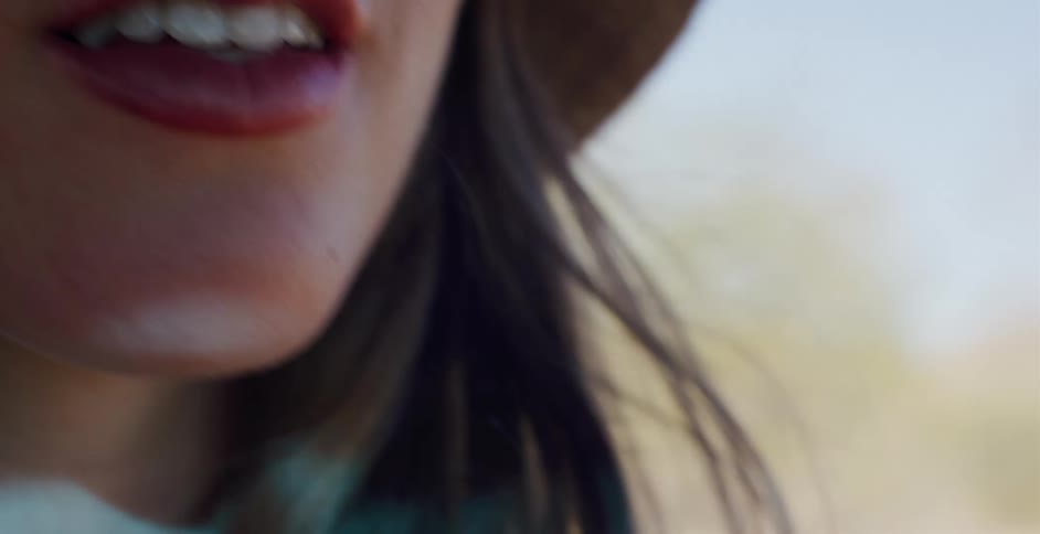 A sensual slow-motion close-up of a woman's mouth and hair blowing in the wind on a sunny day