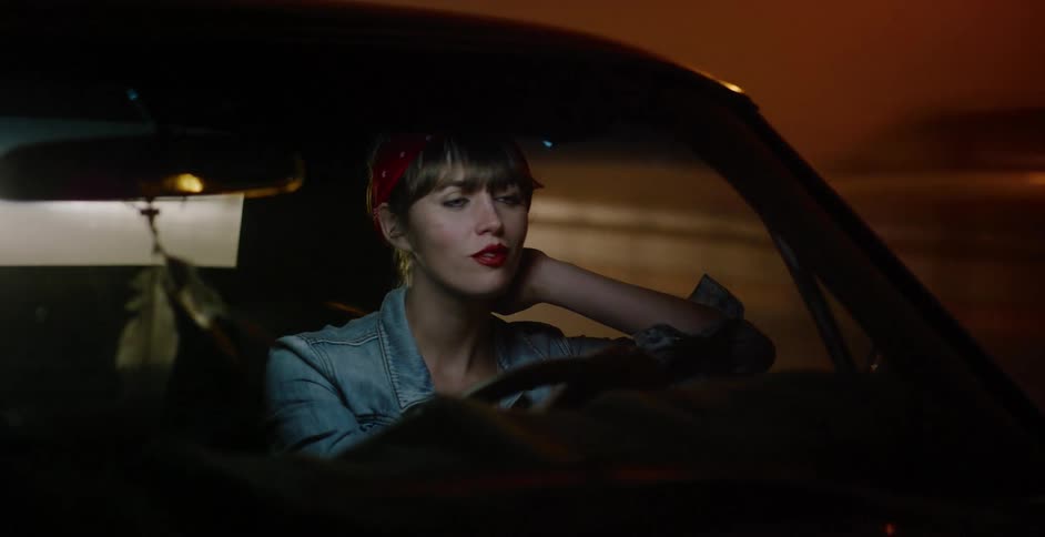 A thoughtful woman with retro style drives a classic car through a brightly lit tunnel at night