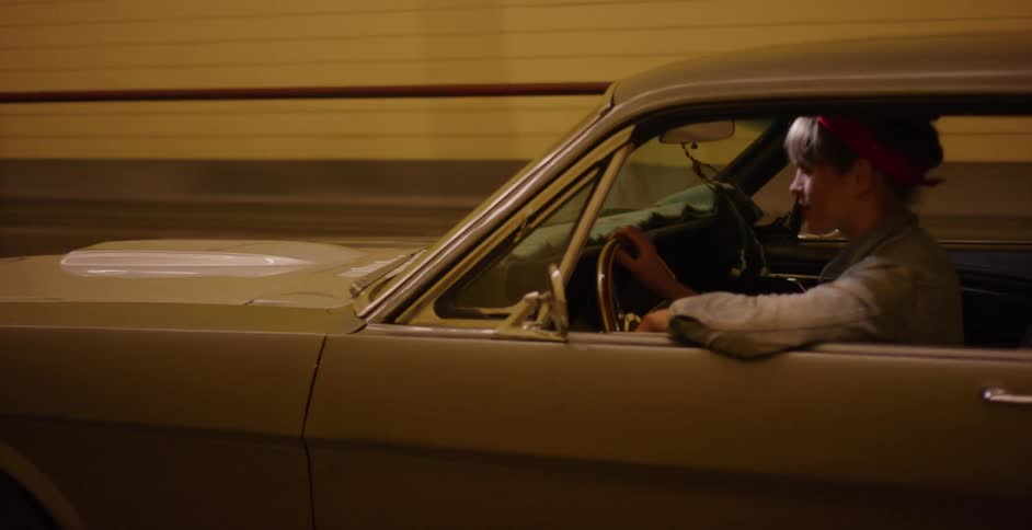 Cool woman with a retro style drives her classic American muscle car through an illuminated tunnel at night