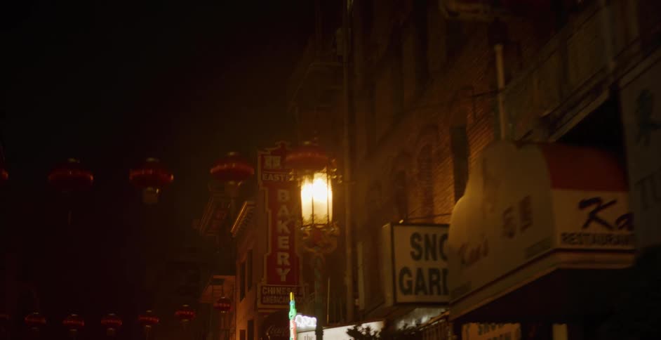 A slow pan down a foggy Chinatown street reveals glowing red lanterns and business signs at night