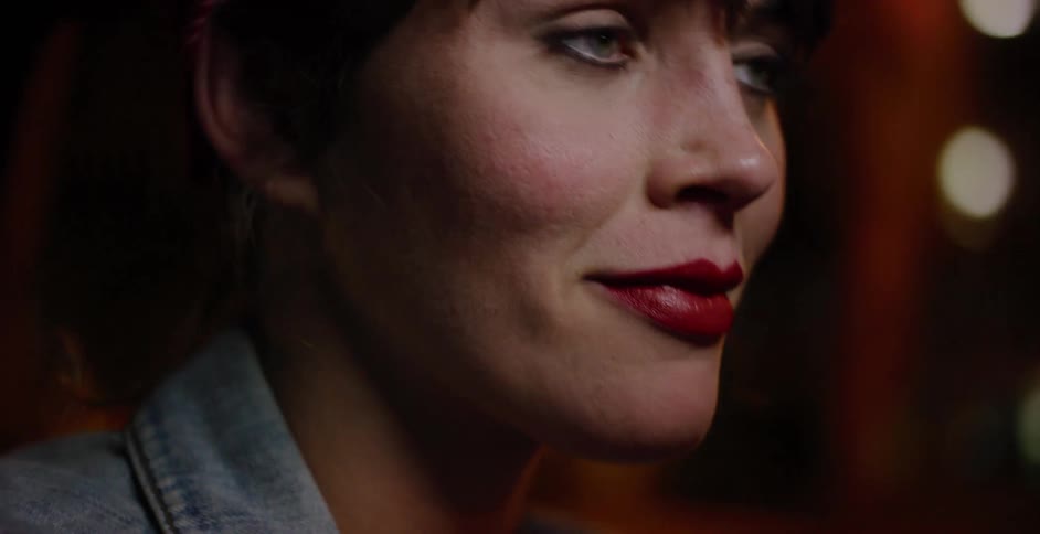 Intimate close-up of a woman's profile with red lipstick as she rides in a car at night, with bokeh city lights passing by