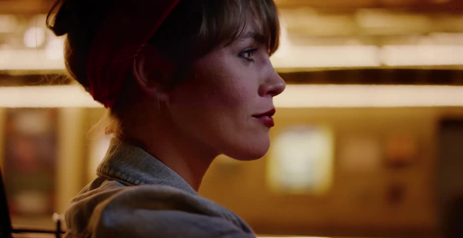 A stylish young woman with a red bandana enjoys the magical lights of a carnival while riding on a carousel at night