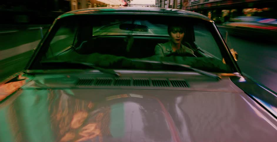A cool woman drives a vintage muscle car through the vibrant, neon-lit streets of a city at night, shot from the hood