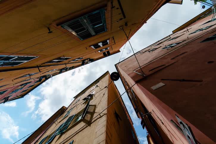 Worm's-eye view timelapse of clouds passing over colorful old European buildings in a narrow alley