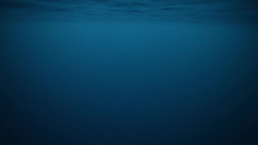 A mysterious underwater view of the deep blue ocean with gentle ripples on the surface