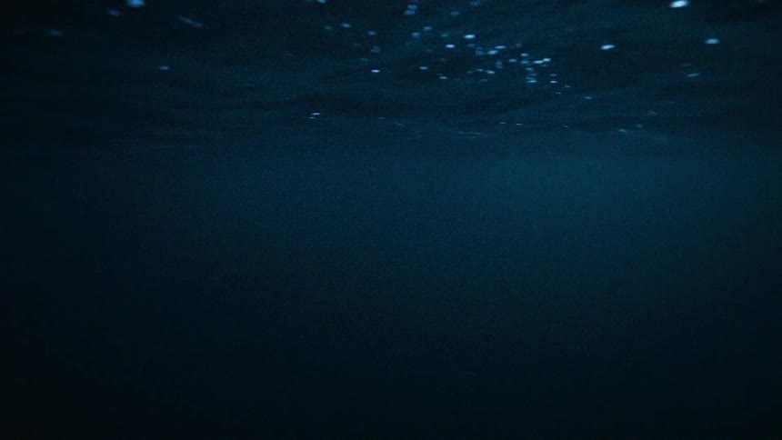 A tranquil yet mysterious underwater view of the deep blue ocean's dark depths