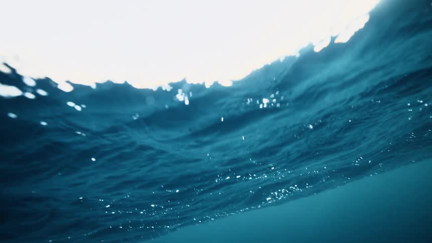 A mesmerizing underwater view of the serene ocean surface with sunlight shimmering through the deep blue water