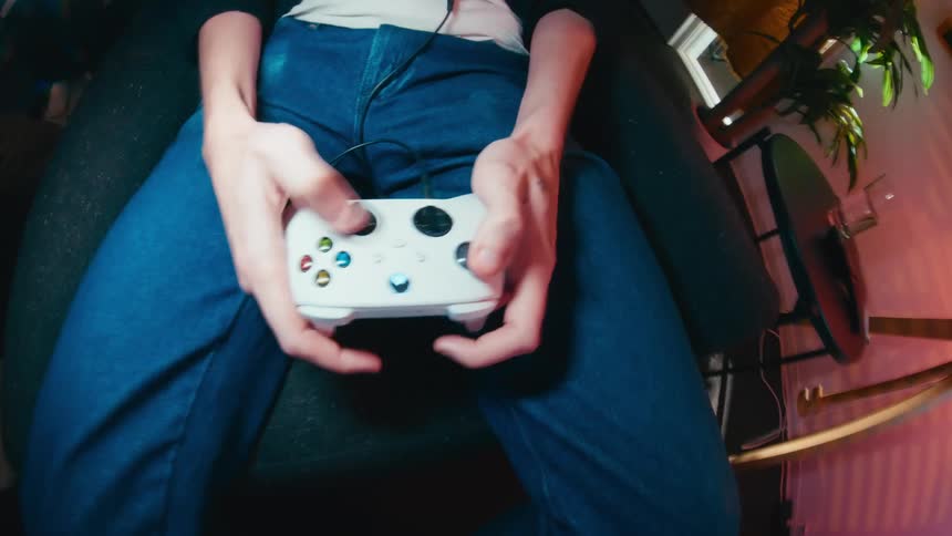 A dizzying point-of-view shot shows a person's hands rapidly using a controller while playing a video game