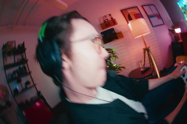 Close-up fisheye view of a man enthusiastically playing a video game with a controller, smiling and laughing in a stylish room