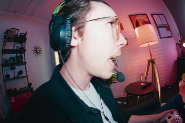 Fisheye close-up of an excited young man wearing a headset while passionately playing video games in his stylish room