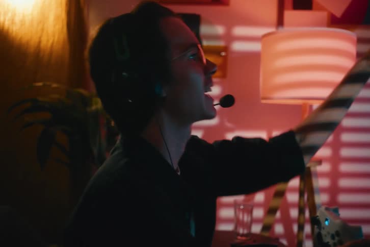 An excited young gamer wearing a headset passionately celebrates a big win while playing video games late at night