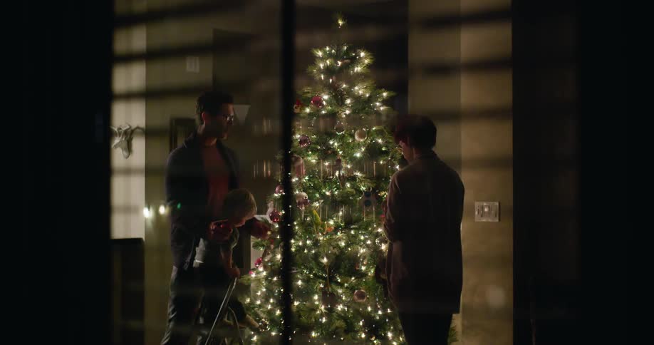 Family decorates their christmas tree at night