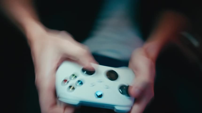 Close-up of a person's hands rapidly moving across a white video game controller while intensely playing