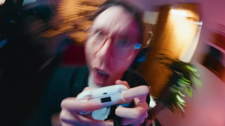 Dizzying fisheye view of an energetic gamer intensely playing a video game and screaming in excitement in a seamless loop