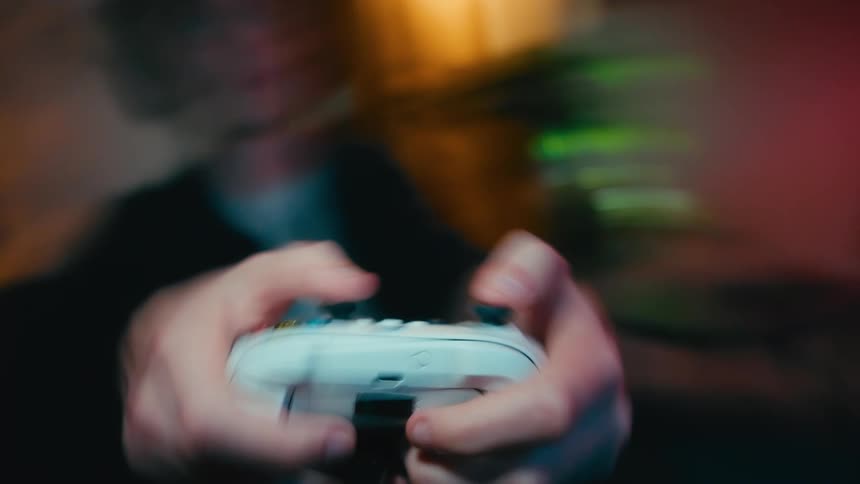 A fast-paced, motion-blurred close-up shows a gamer's hands intensely playing on a white controller