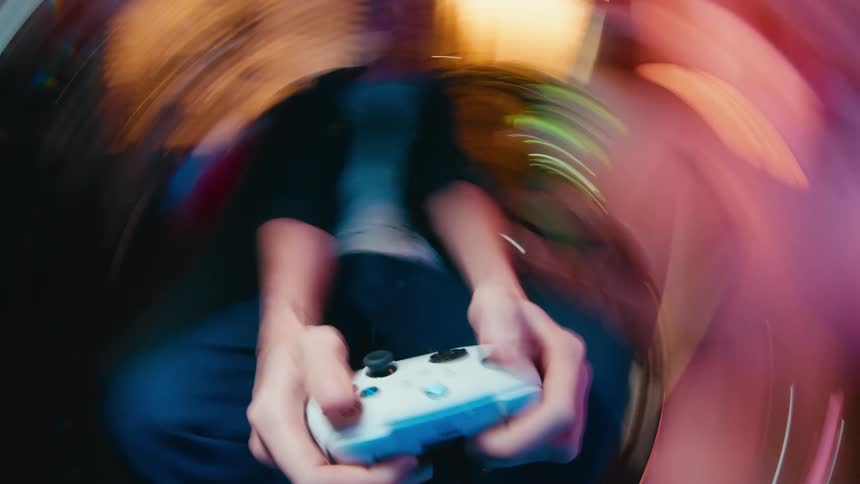 A disorienting, looping, fisheye close-up shows a young man's hands frantically playing a video game on a controller