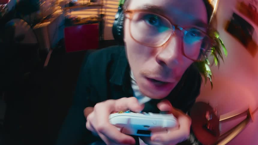 A distorted, wide-angle close-up of a man's expressive face as he intensely plays a video game with a controller