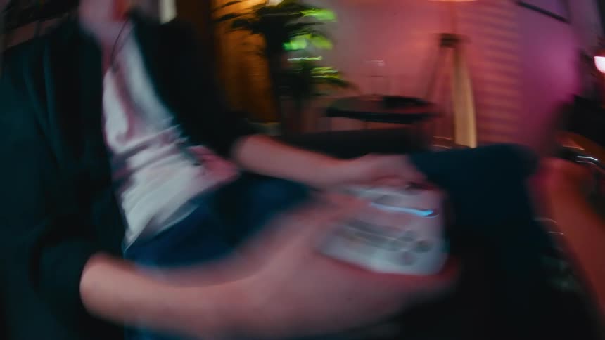 A dizzying and disorienting close-up perspective of hands on a controller during an intense video game session in a neon-lit room