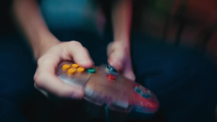 A hyped gamer frantically plays with a retro Nintendo 64 controller in a fast-paced, shaky close-up