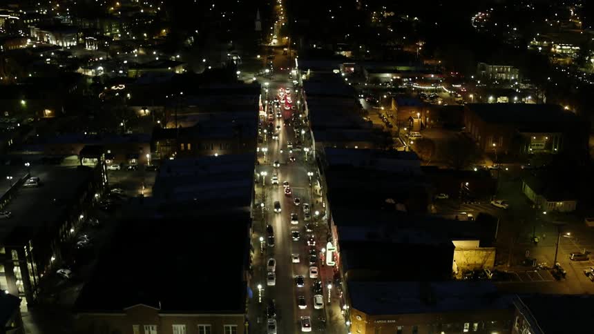 Traffic is flowing down a long city street at night