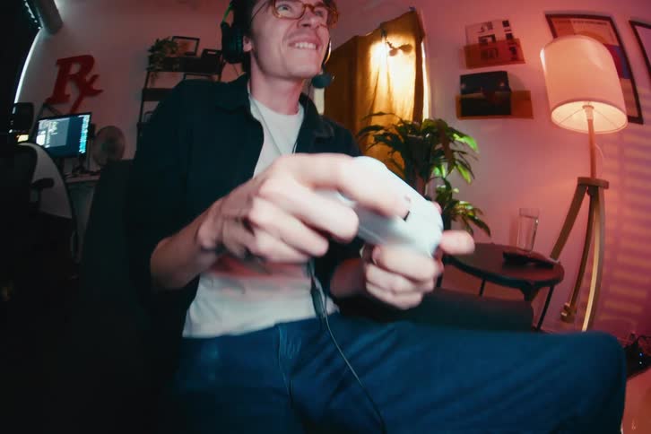 A dynamic fisheye shot reveals an expressive young gamer with glasses and a headset intensely playing video games in his room