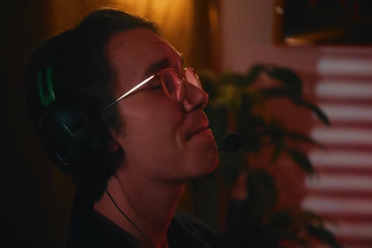 Vertical close-up of an excited young gamer wearing a headset and glasses, celebrating a victory while playing a video game