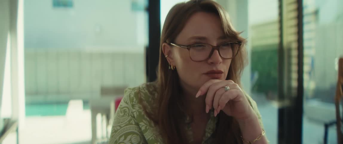 A close-up shot shows a focused woman in glasses with her hand on her chin, deep in thought while working in a modern home