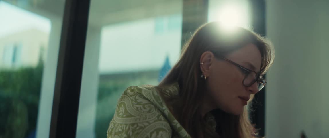 Close-up of a thoughtful woman in glasses concentrating on her work by a sunny window