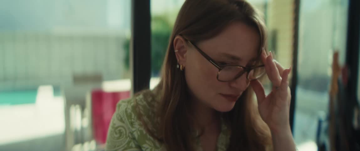 A young professional woman types on her laptop before thoughtfully putting on her glasses to continue her work