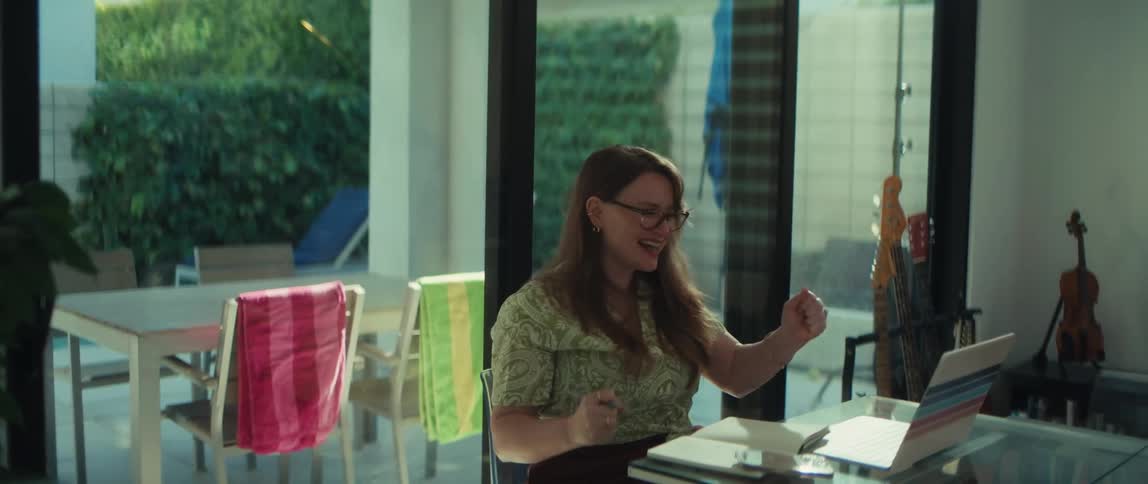 An ecstatic woman working from home celebrates a big win she sees on her laptop in triumphant slow motion