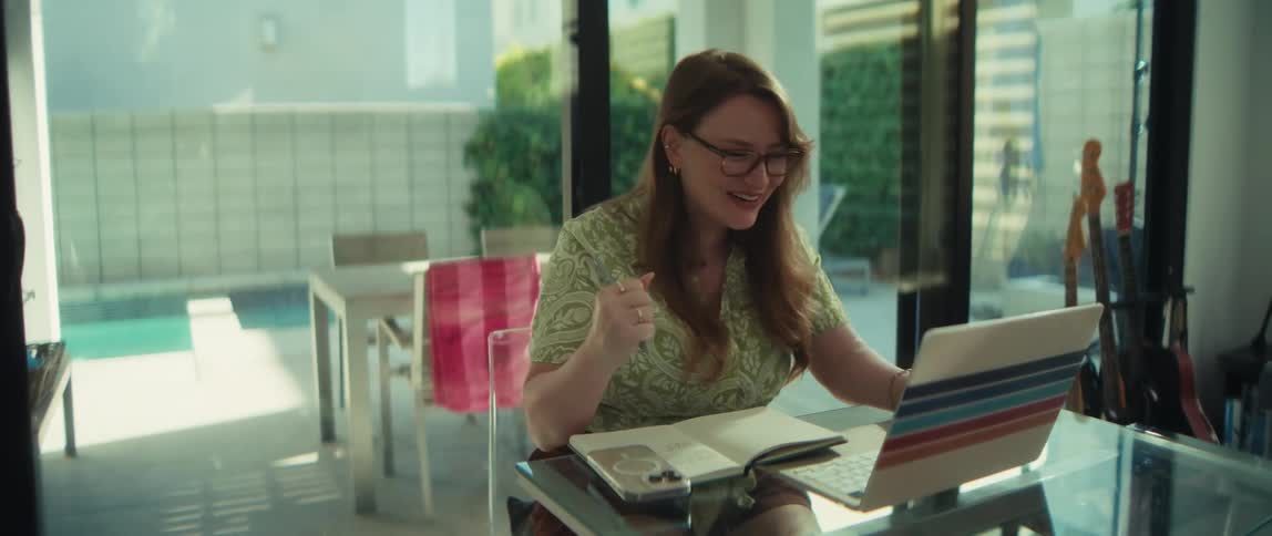 An excited woman working from home in a modern house celebrates and fist pumps after receiving great news on her laptop