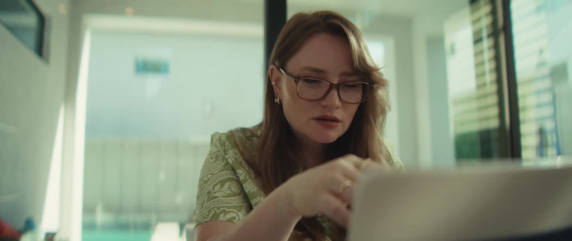 A thoughtful woman works from home on her laptop, contemplating a problem and then smiling as she finds the solution