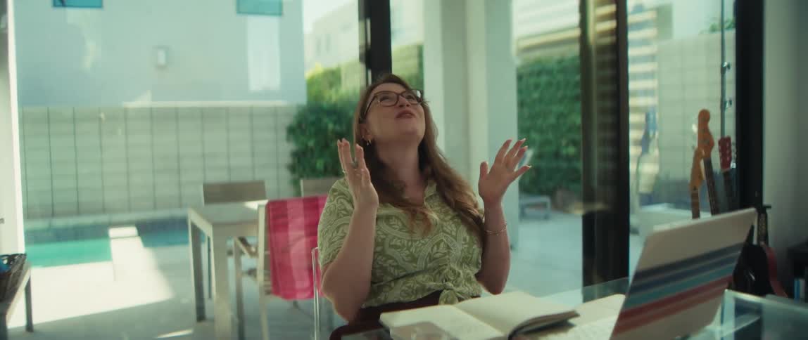 A young woman working from her sunlit home office erupts in celebration after getting good news on her laptop