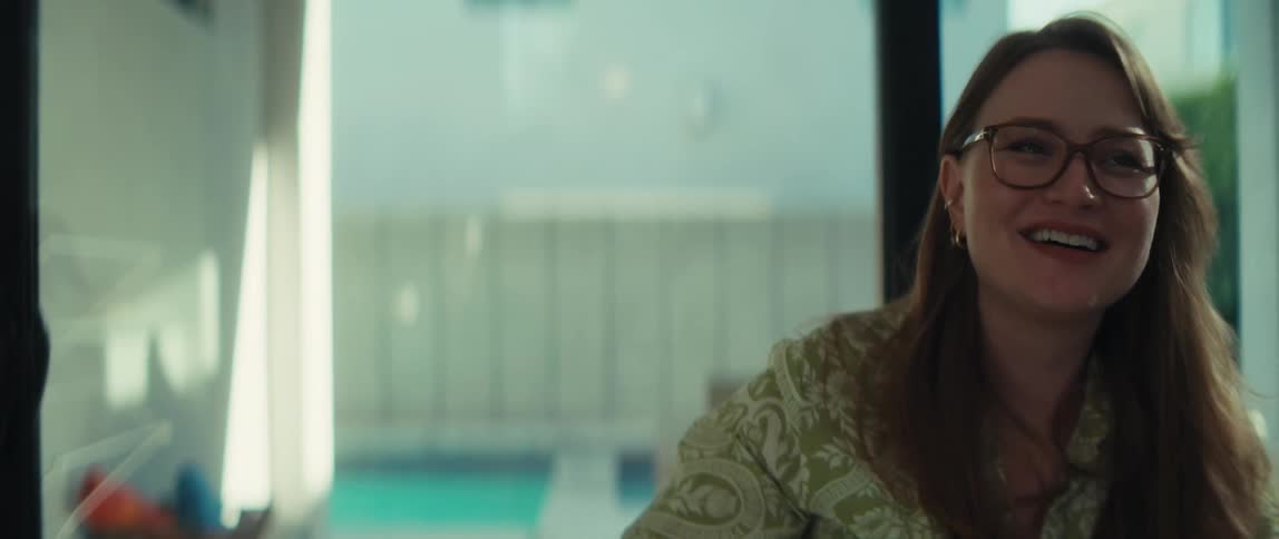 A happy woman in glasses laughs and fist pumps in celebration while working indoors, filmed in slow motion