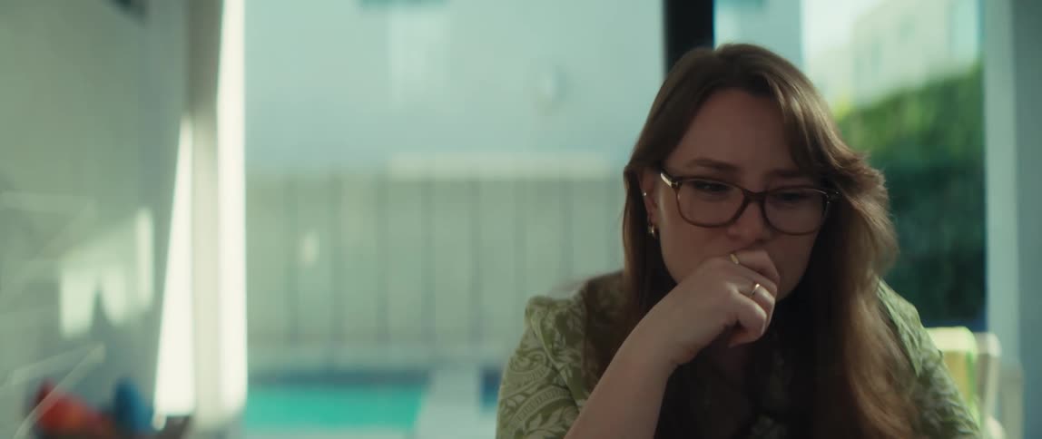 A young woman wearing glasses has a moment of realization while working, removing her glasses in surprise before breaking into a happy smile