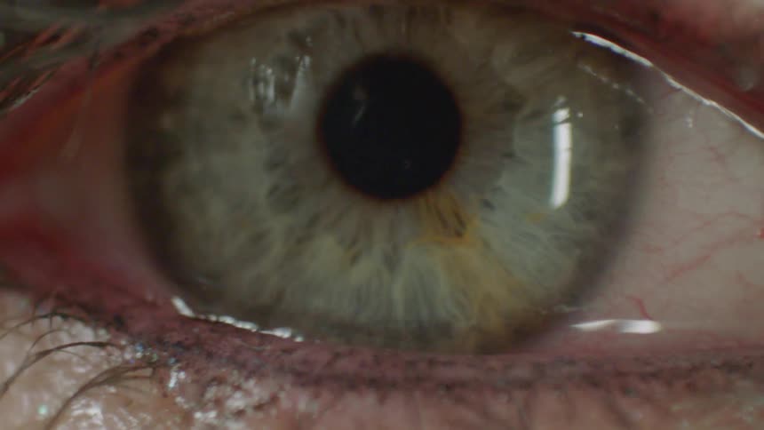 A detailed macro shot shows a human green eye with makeup slowly zooming in
