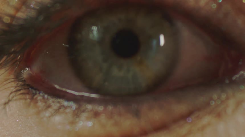 A stylistic extreme close-up shot of a human eye with glittery makeup looking directly into the camera
