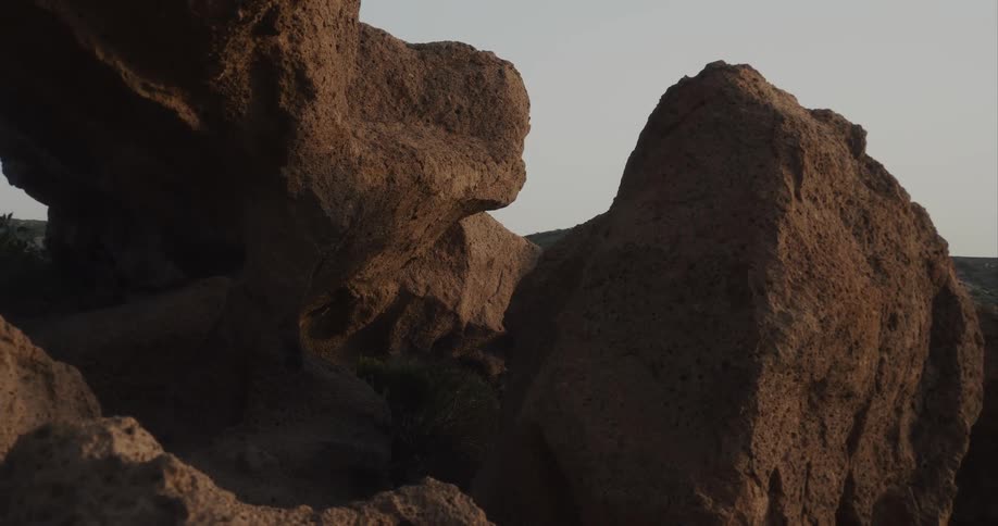 A slow camera zoom-out reveals the intricate textures of a majestic rock formation at dawn
