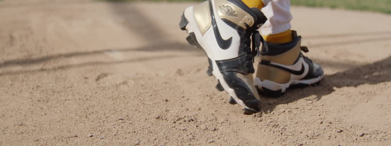 Slow motion close-up of a baseball player's cleated shoes stepping on the infield dirt and walking away