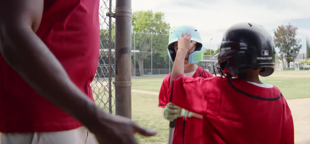 A young little league player is comforted by his teammates and coach in the dugout after a tough moment in the game