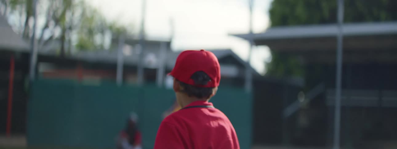 A young pitcher throws a baseball in slow motion to a catcher and batter during a little league game