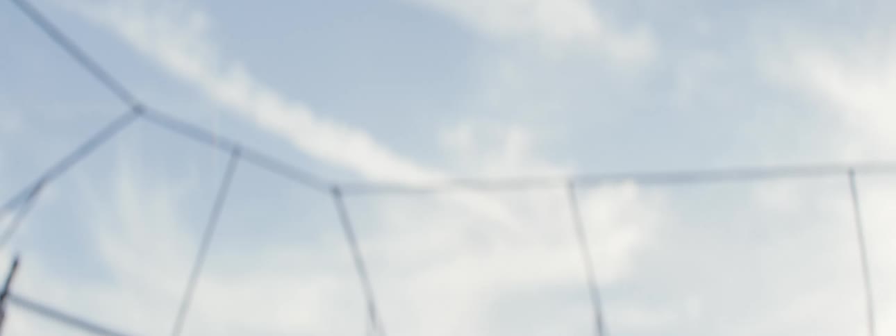 Slow motion shot of a baseball being thrown up and falling against a cloudy blue sky in a batting cage