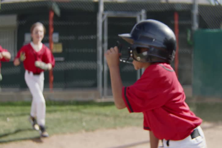 A young baseball player slides safely into home plate and is swarmed by his excited teammates for a celebratory huddle