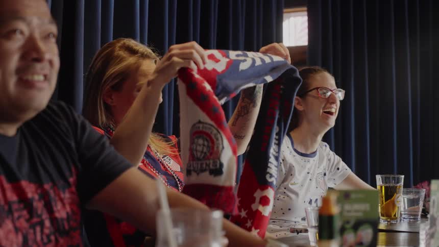 Excited American soccer fans in patriotic gear cheer and celebrate enthusiastically while watching a game at a sports bar