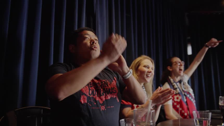 Passionate soccer fans erupt in slow-motion celebration as they watch their team score a goal in a sports bar