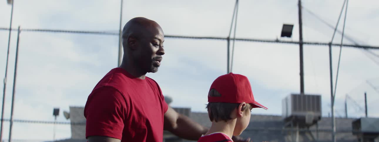 In slow motion, a dedicated baseball coach mentors a young pitcher on the field before he throws the ball