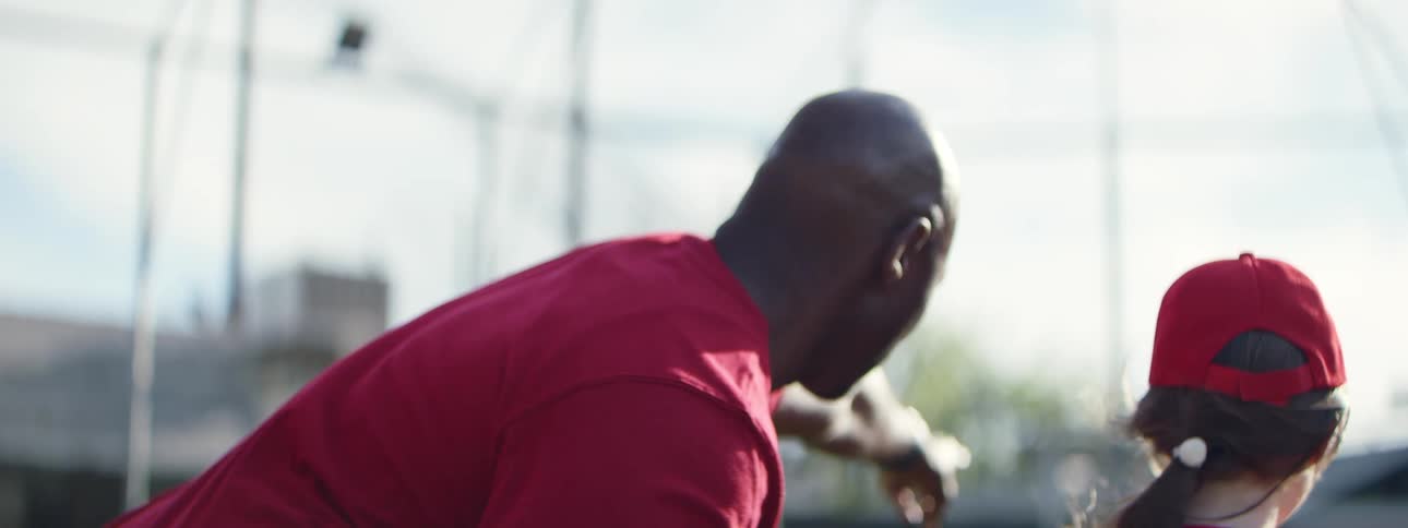 A little league coach instructs his pitcher on the mound before she throws the ball in slow motion